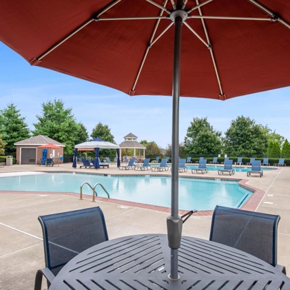 Two sparkling swimming pools bordered by cozy lounge chairs, shaded tables, umbrellas, and a spacious sundeck adjacent to a charming gazebo.